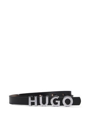 Černý kožený pásek se stříbrnými písmeny tvořícími nápis "HUGO" jako přezka, položený na bílém pozadí.