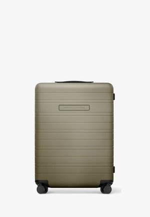 Valise rigide compacte vert olive avec des rainures horizontales, quatre roues noires pivotantes et une poignée supérieure noire.