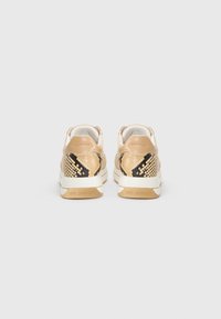 Des baskets présentant une palette de couleurs beige et or, avec des accents en cuir texturé façon serpent, et une semelle blanche arborant "LOVE MOSCHINO" embossé au talon.