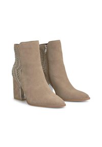 Botines de ante beige con punta afilada, panel de acento plateado, detalles texturizados y tacón cuadrado. Cierre lateral con cremallera para facilitar su uso.