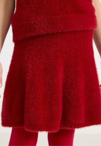 Red fuzzy knit dress featuring a flared bottom and a soft texture, with a matching red seamless layer underneath.