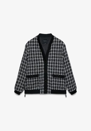 Cardigan à motifs noir et blanc avec col en V, boutons sur le devant et deux poches. Comprend des poignets et un ourlet côtelés. Confectionné en tissu texturé.