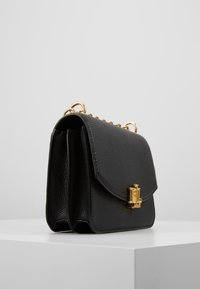 Czarna skórzana torebka o teksturowanej powierzchni, klasycznym zamknięciu na klapę, złotych elementach i krótkim pasku z łańcuszkiem. Posiada dwie przegrody.