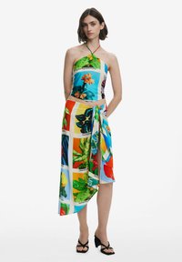 Abito stampato colorato con design a collo halter, caratterizzato da un mix di motivi floreali e forme geometriche nei toni di blu, verde, arancione e giallo.
