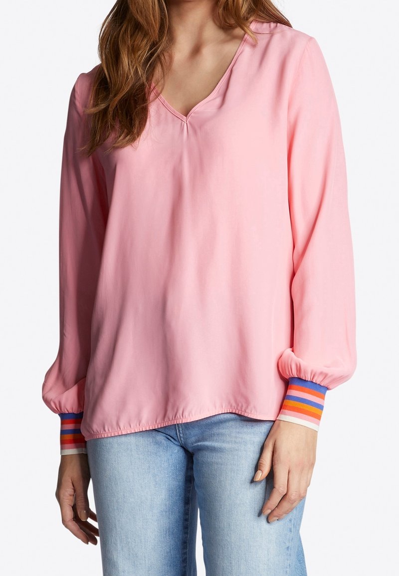 Blusa rosa a maniche lunghe con scollo a V, con polsini a righe arancioni, blu e bianchi. Tessuto morbido e vestibilità comoda.