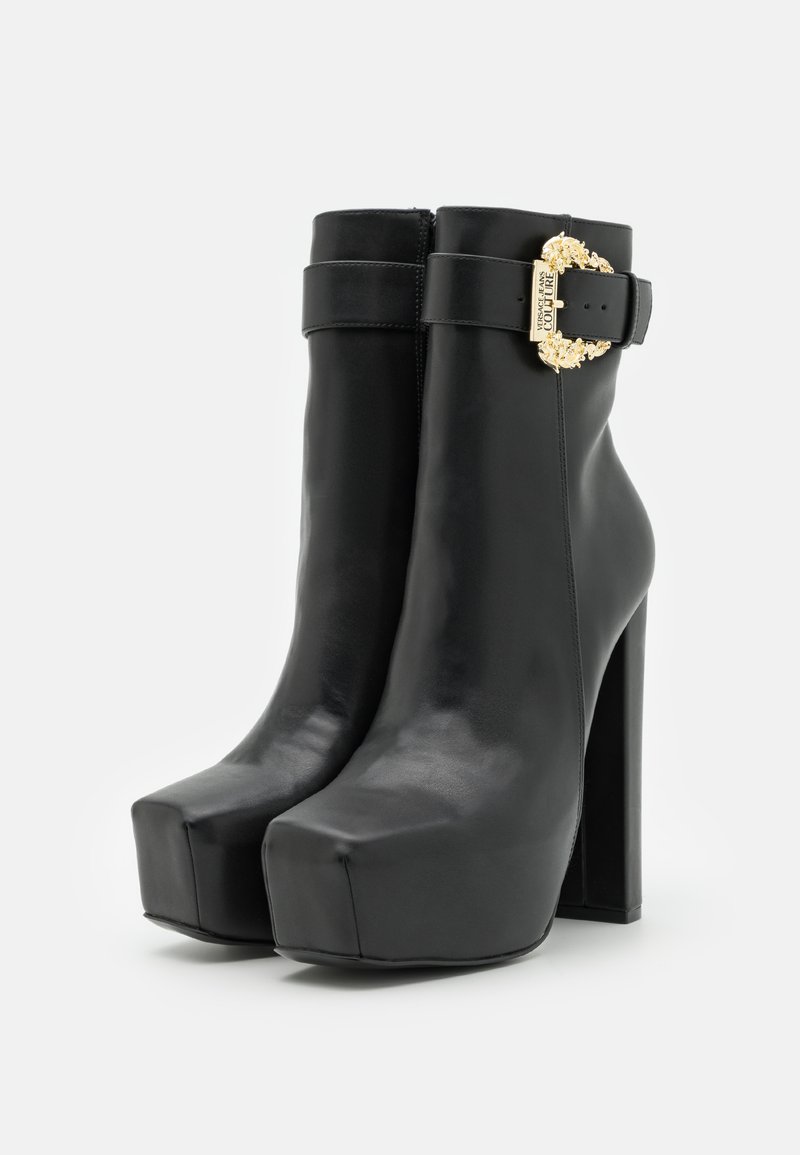 Stivali alla caviglia in pelle nera con plateau, punta squadrata, tacco a blocco alto e una fibbia decorativa dorata con dettagli del marchio sulla cinghia.