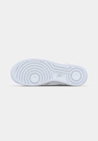 Hvid sneakersole med cirkulære mønstre og teksturerede kanter. Har Nike-branding, lavet af gummi med en glat, holdbar overflade.