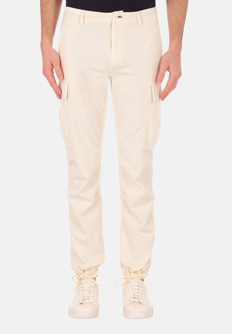 Beige cargobroek met zijzakken, gemaakt van duurzaam materiaal. Glad textuur, aangesloten taille en smalle enkels. Gecombineerd met lichte sneakers.