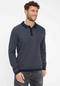 Polo a maniche lunghe blu navy con un motivo testurizzato, colletto a contrasto e una patta con tre bottoni. Il tessuto sembra morbido e confortevole.