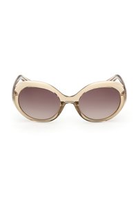 Lunettes de soleil ovales surdimensionnées avec montures beige translucides et verres dégradés marron, présentées de face sur un fond blanc.