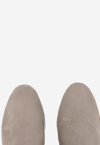 Top view of light beige suede shoes with rounded toes on a plain white background.