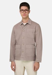 Helles Taupe-Jackett aus Baumwolle mit Kragen, durchgehender Knopfleiste und zwei aufgesetzten Taschen vorne. Glatte Textur.