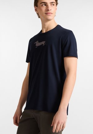 Marineblauwe T-shirt met korte mouwen, gemaakt van zacht materiaal, met een geblokte teckel afbeelding op de borst. Gladde textuur, klassieke pasvorm.