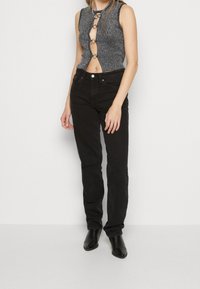 Sorte straight-leg jeans med høj talje og fem lommer, parret med en ærmeløs, grå, ribbet striktop med cirkulært hardware.