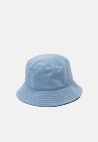 Chapeau seau en denim bleu clair avec une couronne arrondie et un large bord plat. Présente des coutures verticales et une texture douce.
