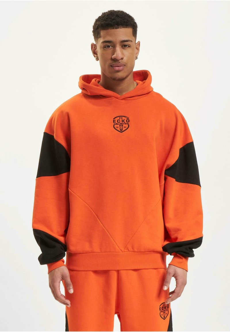 Oransje hettegenser med svarte detaljer, med et frontlogo og ribbede mansjetter. Laget av mykt stoff, med en avslappet passform og geometriske sømmer.