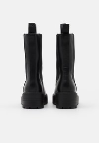 Black leather ankle boots with elastic side panels, flat rubber soles, and rear pull tabs. Sleek design with a smooth texture.