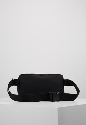 Sort rektangulær bæltetaske med justerbar rem og plastikspænde, placeret på hvid overflade mod en ensartet lys baggrund.