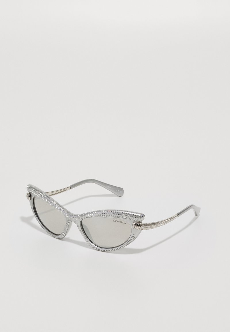 Óculos de sol em forma de gato com armação prateada e lentes fumadas, adornados com aplicações de cristal ao longo das bordas e das hastes.