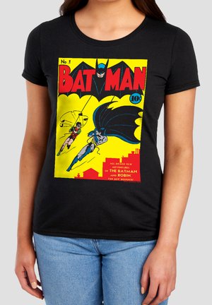 Woman wearing black T-shirt featuring vintage Batman comic cover with Batman and Robin swinging above city rooftops.