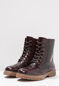 Botas de cuero burdeos con cordones y detalles de brogue, con puntera redonda y suela de goma texturizada. Acabado suave.