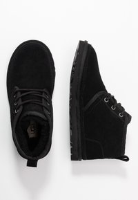Svarta mocka ankla boots med en texturerad yta, rund tå, snörning och en gummisula. Har en liten dragflik vid hälen.
