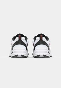 Hvide sneakers med sorte accenter og et rødt logo på hælen. Har en polstret sål og teksturerede områder for greb og støtte.