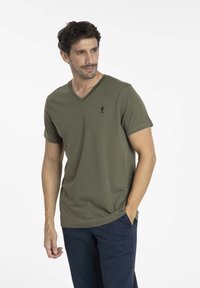 T-shirt vert olive en V en tissu doux, à manches courtes, avec un petit logo noir sur la poitrine gauche. Conçu pour un ajustement décontracté.