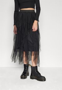 Black tulle tiered skirt with an elastic waistband, layered design, and knee-length. Worn with lace-up black combat boots.