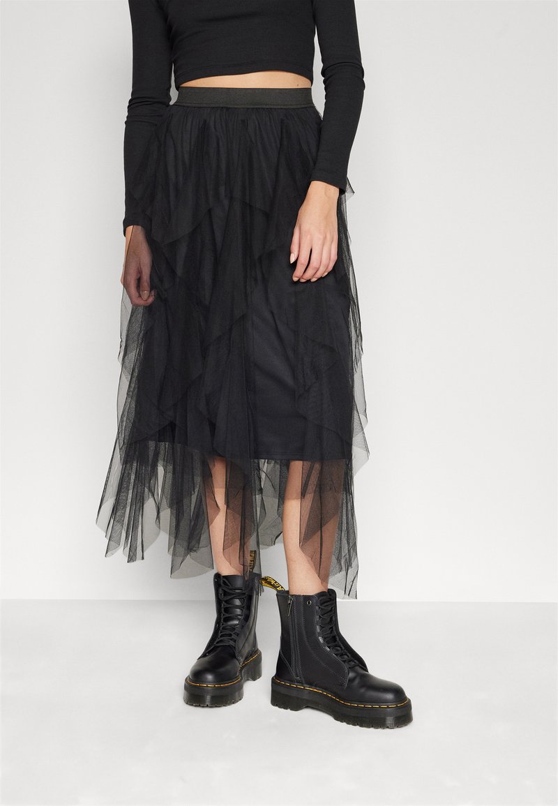 Black tulle tiered skirt with an elastic waistband, layered design, and knee-length. Worn with lace-up black combat boots.