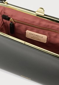 Mustast Itaalia nahast kott, millel on kuldsed detailid. Sisevoodriks on bordo värvi kangas, sees on lukuga tasku ja silt, millele on pressitud „Coccinelle”.