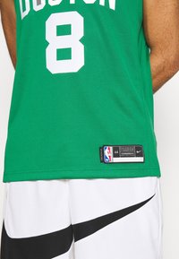 Camiseta de baloncesto verde con el texto en blanco "BOSTON" y el número "8". Fabricada con tejido transpirable, presenta una etiqueta con las marcas de la NBA y Nike.