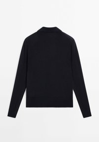 Musta pitkähihaisen neuleen, jossa on kauluspaita, ribbaudet hihansuissa ja helmassa. Suunnitelmaltaan yksinkertainen; sileä pinta ilman näkyviä kuvioita tai lisäyksiä.