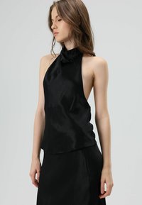 Zwarte zijden haltertop met een gladde textuur, hoge hals, open zijkanten en een vloeiende silhouet.