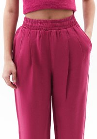 Fuksia leveät housut joustavalla vyötäröllä, joissa on sivutaskut ja pleaatit lisäyksinä. Housut on valmistettu kevyestä kankaasta.