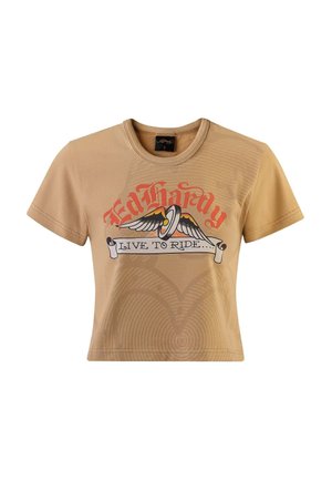 T-shirt courte à manches courtes beige avec un imprimé graphique comprenant des ailes et le texte "Ed Hardy LIVE TO RIDE" en accents rouges et noirs.