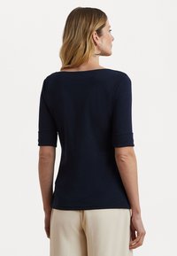 T-shirt bleu marine ajusté avec un large col rond et des manches roulées, en tissu doux, vu de dos.