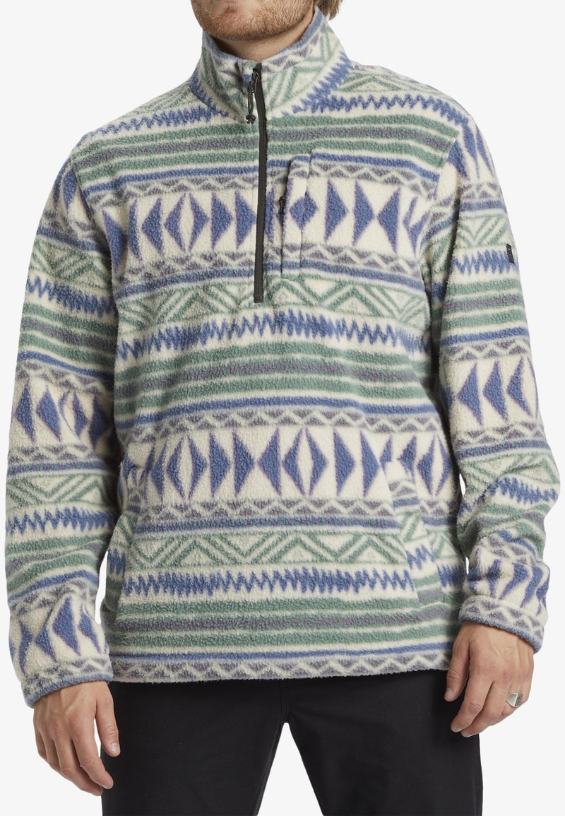 Fleece-pullover med en kvart lynlås, prydet med et flerfarvet geometrisk mønster i grøn, blå og hvid. Blød tekstur med en frontlomme.