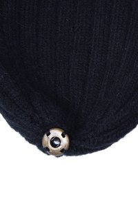 Cappello a maglia nera con texture a coste, dotato di un prominente bottone in ottone al centro in basso e un design morbido.