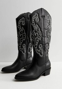 Botas de vaquero de cuero negro con intrincados bordados plateados y acentos de tachuelas, con punta afilada y tacón bajo cuadrado.