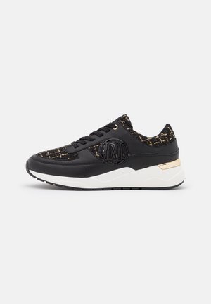 Sort sneaker med tekstureret stof og læderpaneler, hvid sål, guld accent på hælen og præget rundt logo på siden.