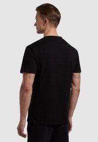 T-shirt nera a maniche corte in cotone; presenta un classico scollo rotondo e una vestibilità comoda, mostrando una texture liscia e un design semplice.