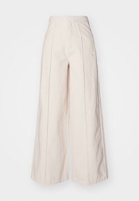 Högmidjade vida gräddfärgade byxor med framseams, subtil Adidas-logotyp på höger lår och textil med struktur.