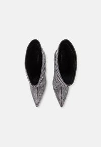 Chaussures argentées scintillantes à bout pointu, recouvertes de strass, avec un intérieur noir et une texture lisse. Conçues pour un enfilage facile.