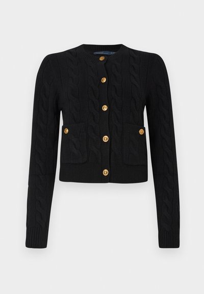 Svart kabelstrikket cardigan med rund hals, lange ermer og to frontlommer; avsluttet med gullknapper og ribbede mansjetter.