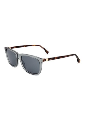 Occhiali da sole quadrati con lenti grigie, montatura frontale grigia traslucida e aste con motivo tartarugato, con un piccolo logo dorato su ogni lato.