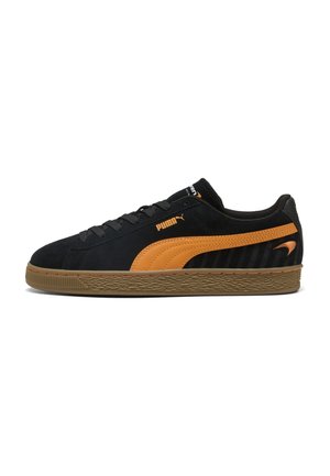 Baskets Puma noires et orange avec semelle en gomme, design à lacets et bande signature Puma sur le côté, montrées de la face extérieure.