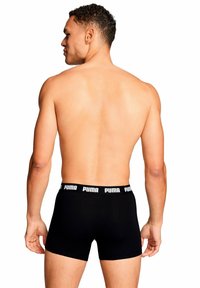 Boxer neri con logo bianco Puma sulla cintura, caratterizzati da una vestibilità aderente e tessuto liscio, mostrati da una vista posteriore.
