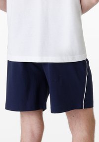 Pantaloni corti in cotone blu navy con una vestibilità morbida, caratterizzati da una striscia laterale bianca a contrasto e una cintura elastica per il massimo comfort.