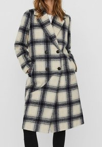 Dobbeltbrystet uldblandingsfrakke med et beige og marineblåt ternet mønster, store notch-kraver og to forlommer. Struktureret stof.